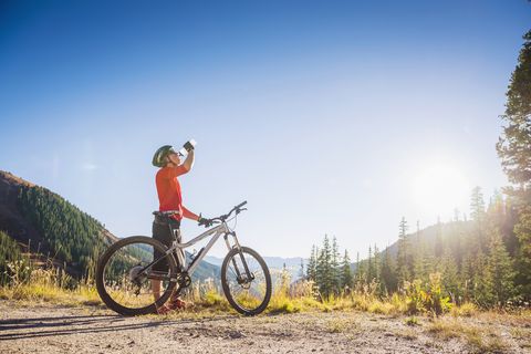 Caucasian man with mountain bike drinking water in mountains