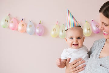 woman holding a happy baby with birthday hat on