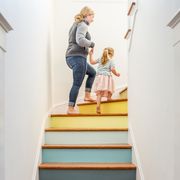 caucasian mother and daughter climbing multicolor staircase