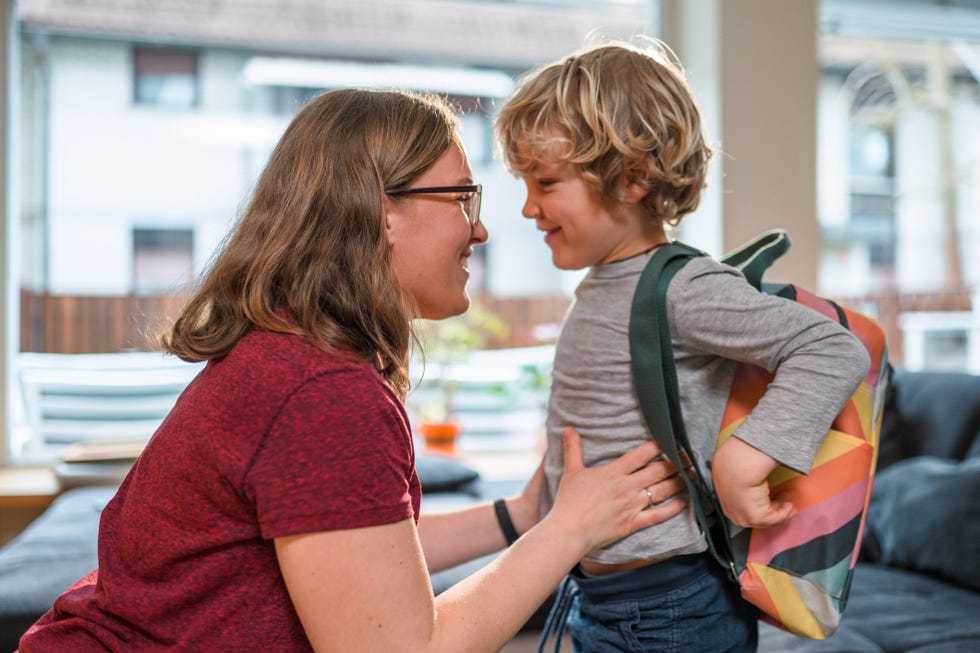 caucasian mother helping her son get ready for school