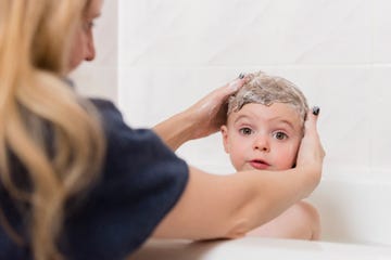 madre lavando cabeza a bebe en banera