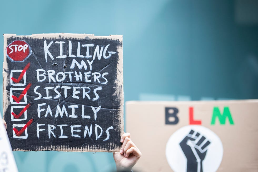 sign that reads 'stop killing my brothers,  sisters, family, friends'