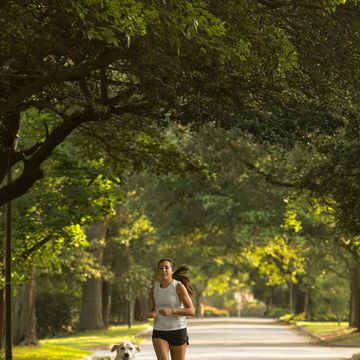 caucasian woman and dog jogging on neighborhood street