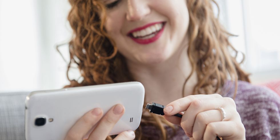 Caucasian woman connecting cord to cell phone