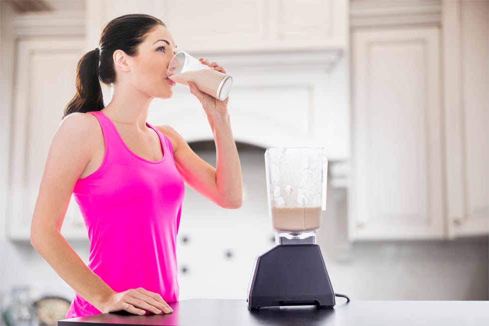 caucasian woman drinking smoothie in kitchen