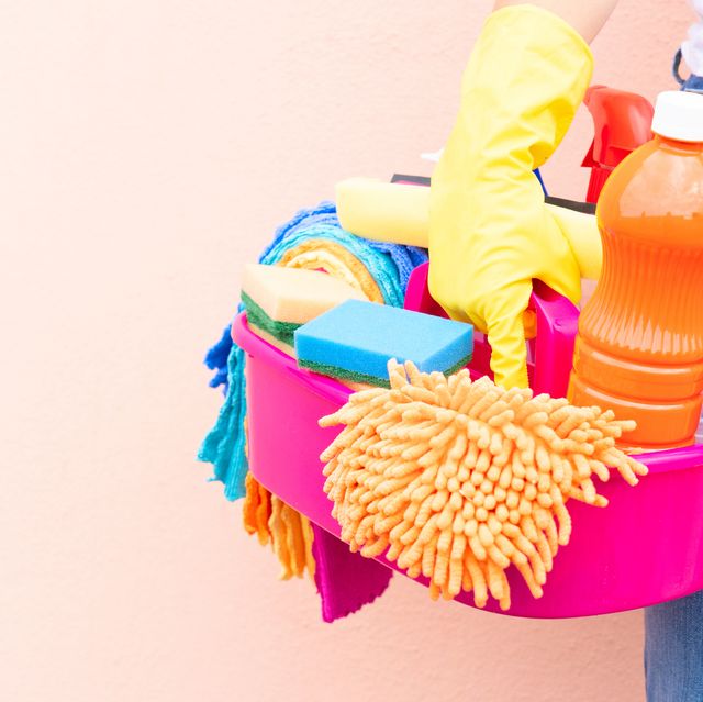 caucasian woman holding basin with cleaning supplies