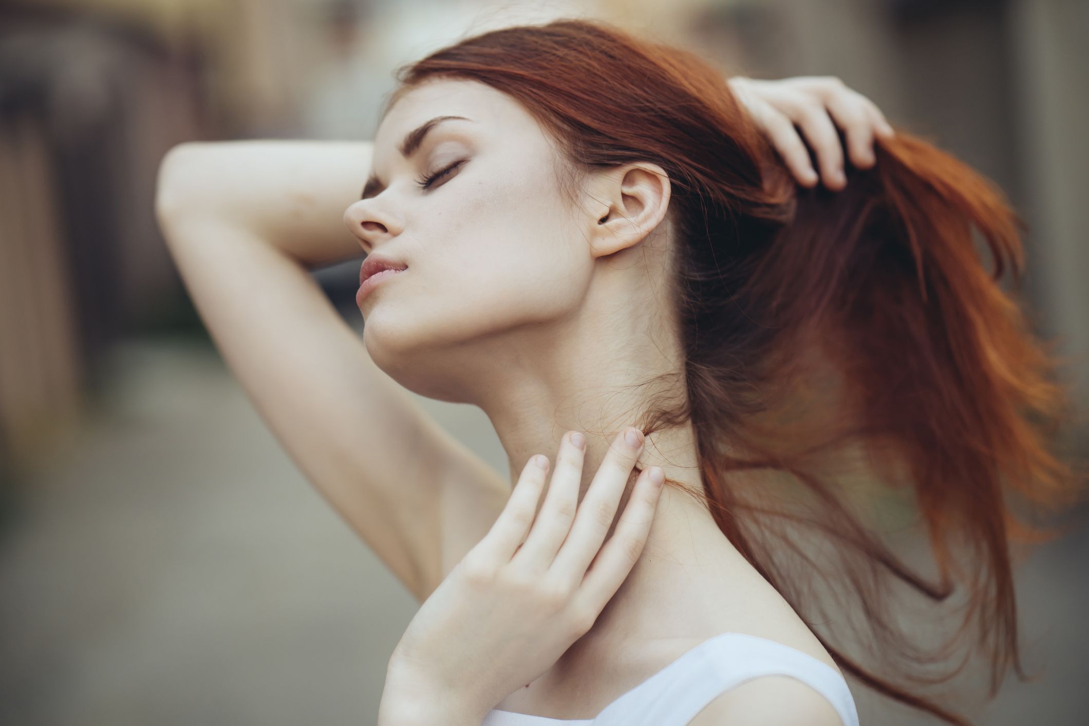 caucasian woman holding hair and rubbing neck