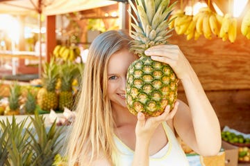 mujer con piña en un puesto de fruta