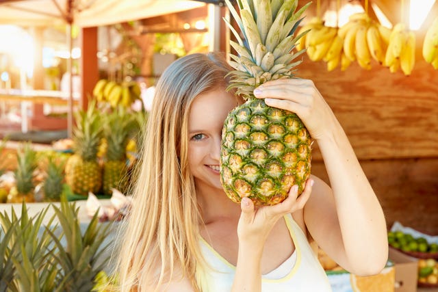 mujer con piña en un puesto de fruta