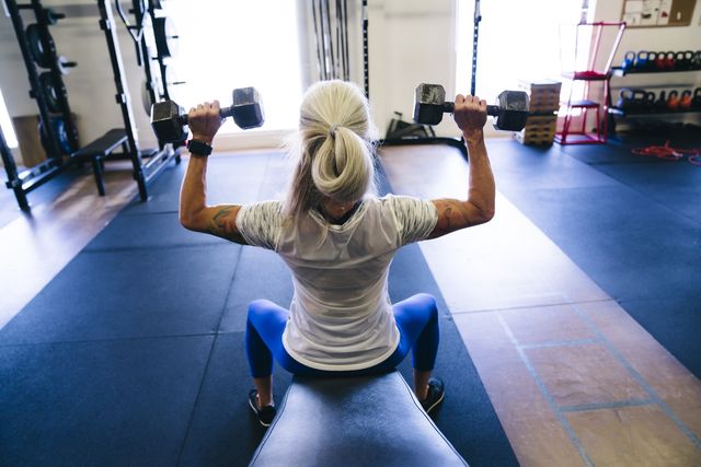 woman lifting dumbbells in gymnasium