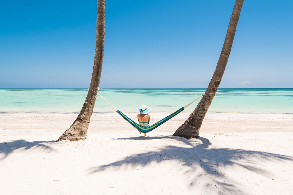 caucasian woman lying on hammock on a tropical beach