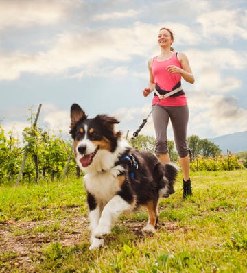 caucasian woman running with dog