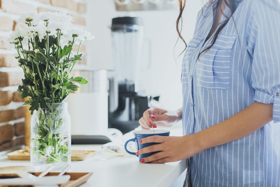 Caucasian woman stirring coffee in kitchen