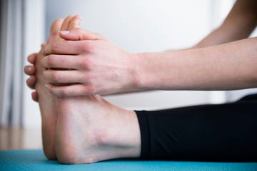 Caucasian woman stretching legs on yoga mat