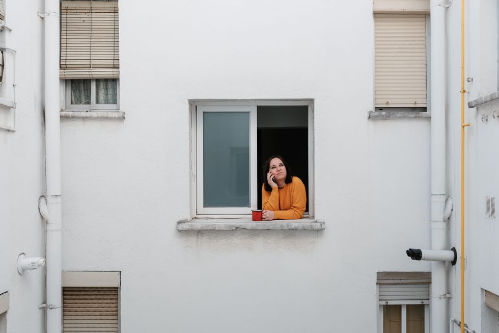 caucasian woman talking on phone while looking out window