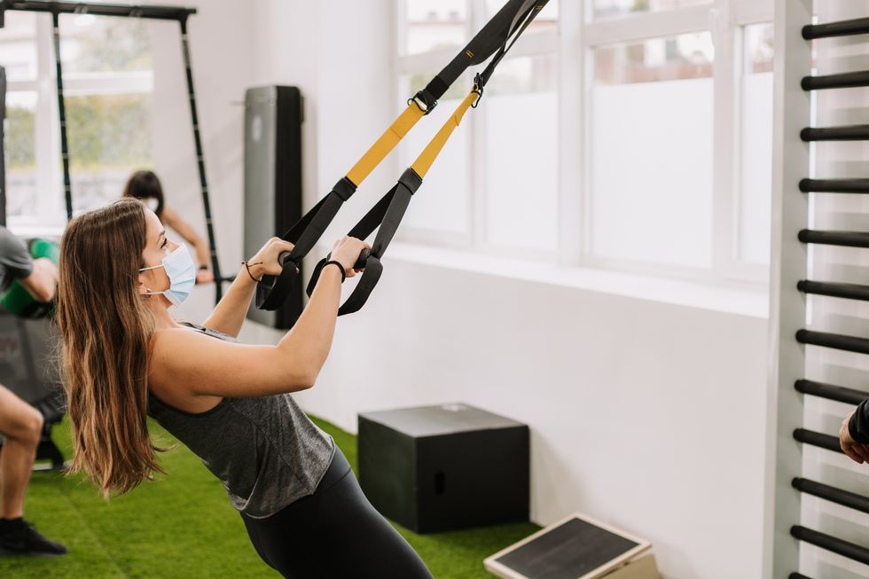 caucasian young woman practicing trx with a personal trainer
