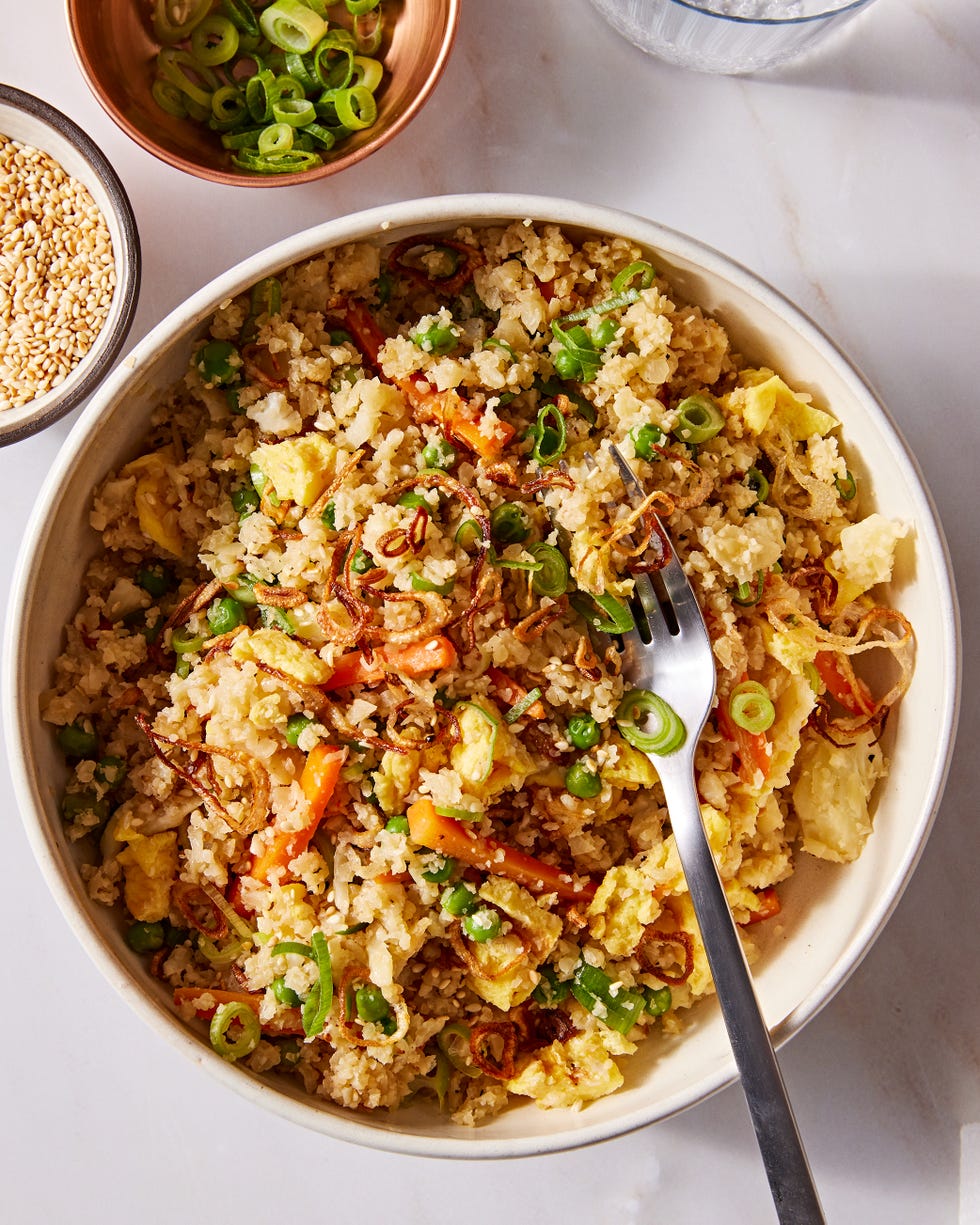 cauliflower fried rice with carrots, green onion, and eggs topped with sesame seeds