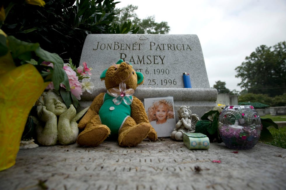 a headstone that reads jonbenet patricia ramsey is surrounded by trinkets