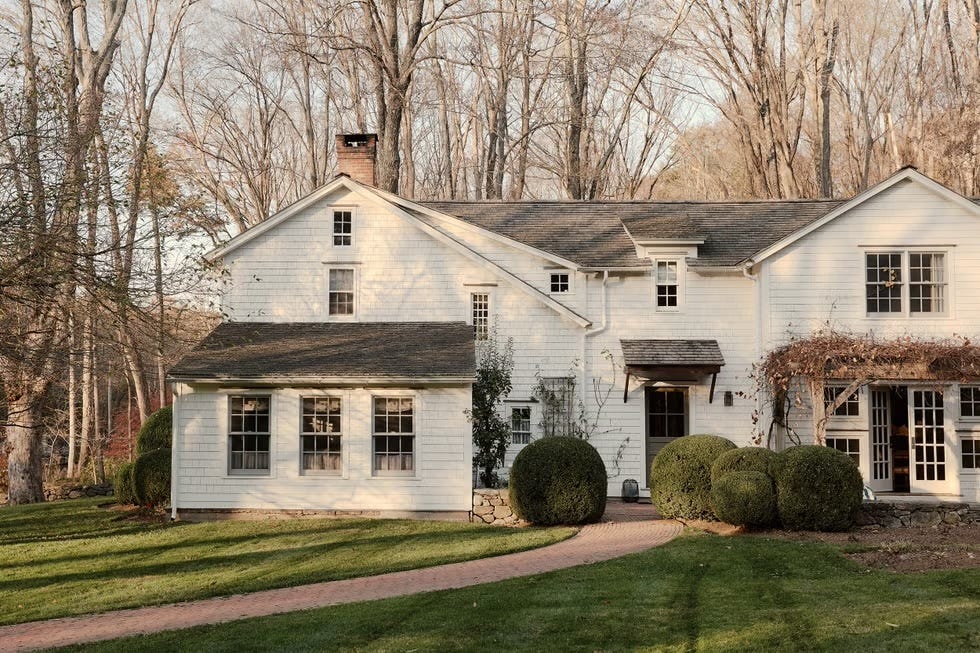Country-style house surrounded by trees and well-kept lawn.