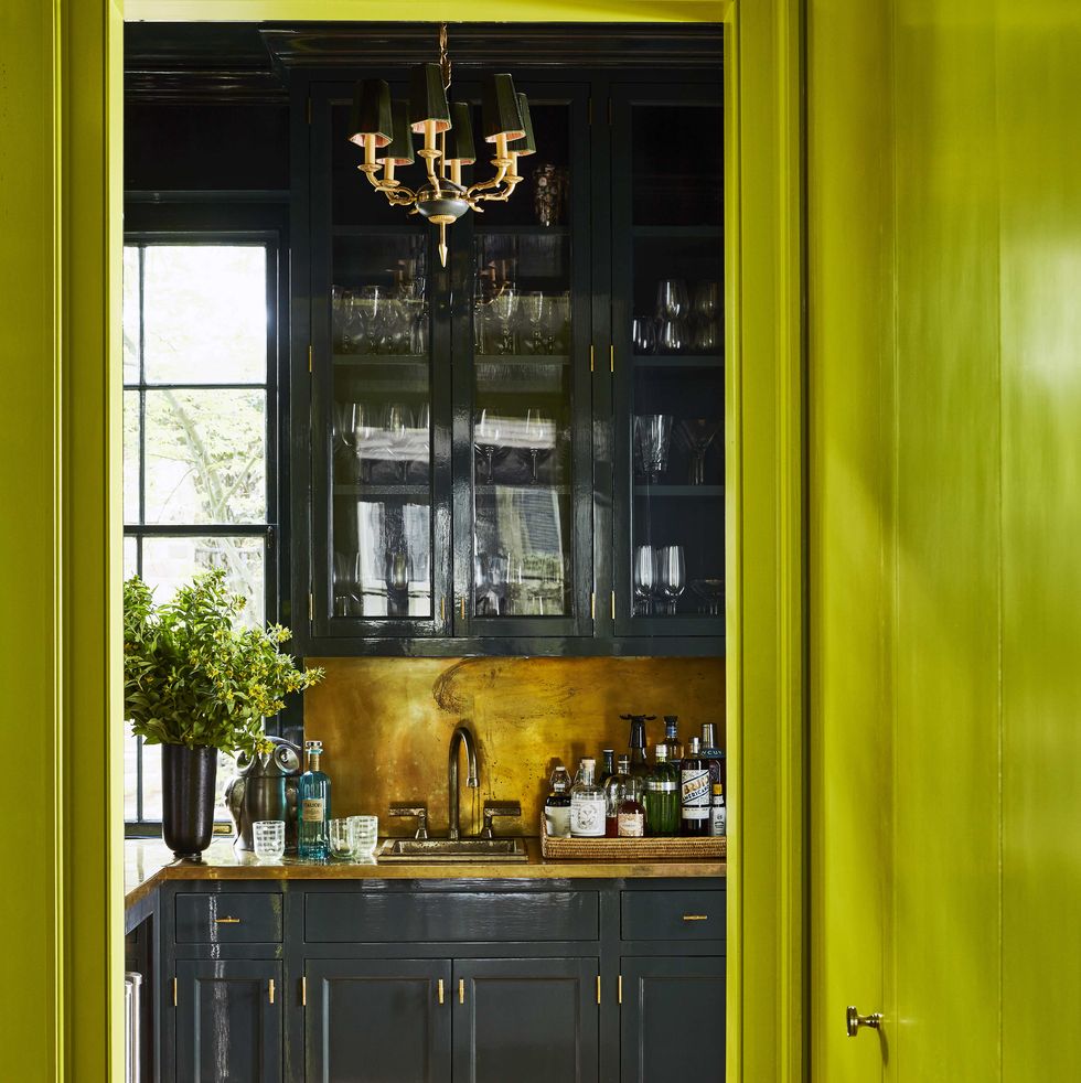 dark glossy cabinets in a bar with brass hardware and countertops and backsplash