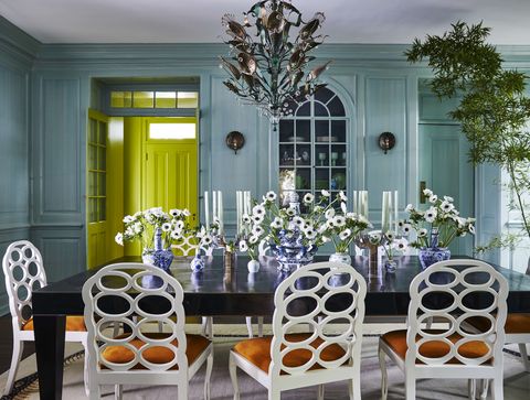 a robins egg blue dining room with a long dining table surrounded by chairs and topped with flowers