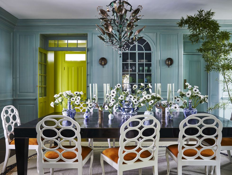 a robins egg blue dining room with a long dining table surrounded by chairs and topped with flowers