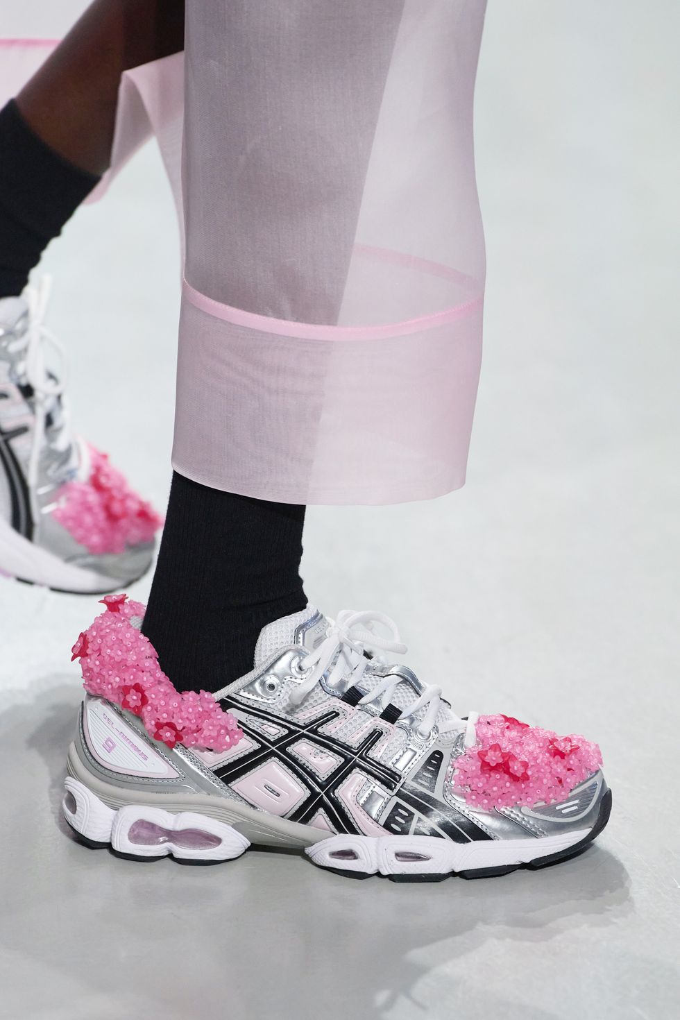 a woman's feet wearing white and pink shoes