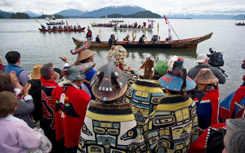 Tijdens een aankomstceremonie begroeten leden van de Auke Bayclan van de Tlingitstam kanos die aankomen op het strand van de Auke Recreation Area in Juneau Alaska