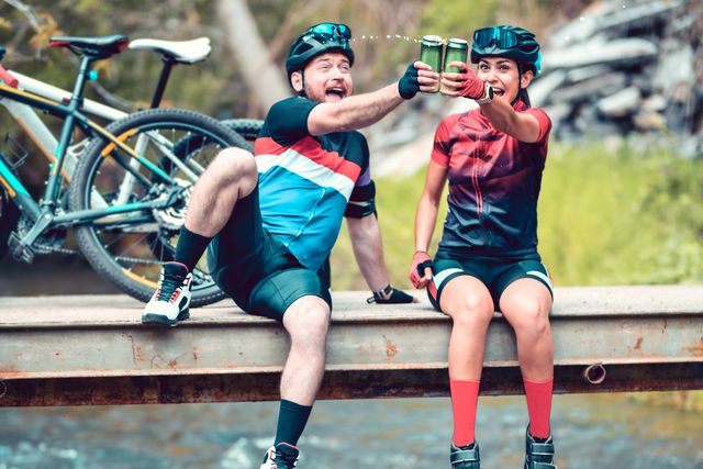celebratory toast with beer by cyclist couple enjoying favorite hobby
