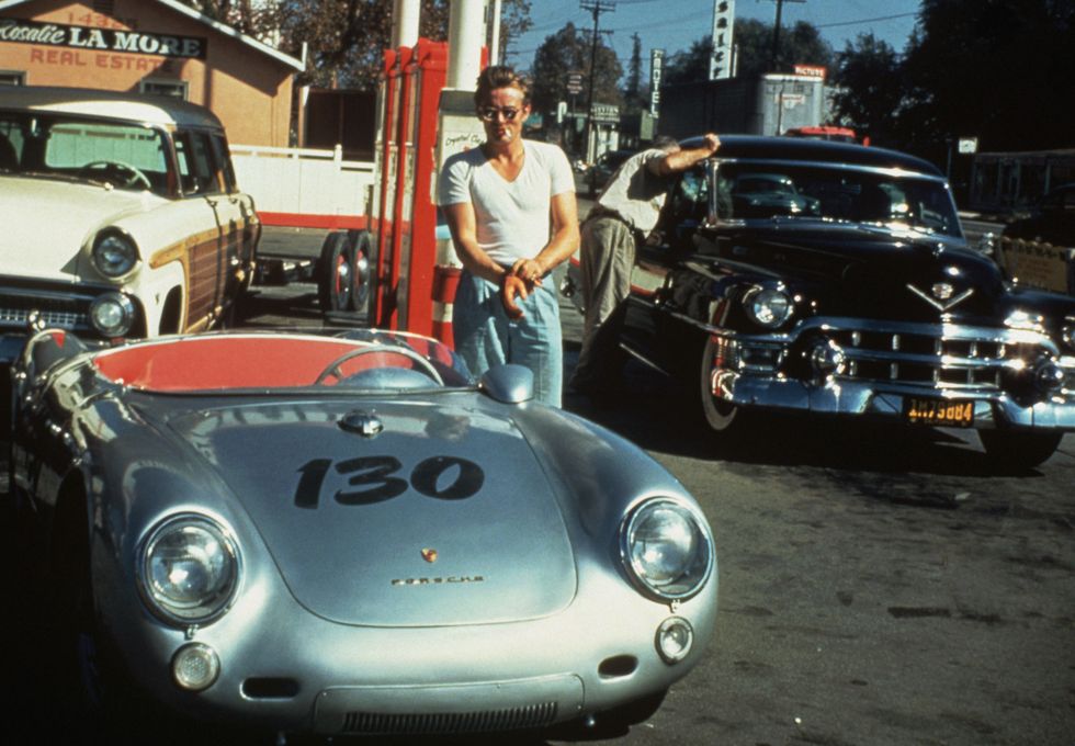 Celebrities and Their Fast Cars: Just hours before his crash, James Dean takes a cigarette break at a gas station next to his beloved silver Porsche 550 Spyder that he named Little Bastard.