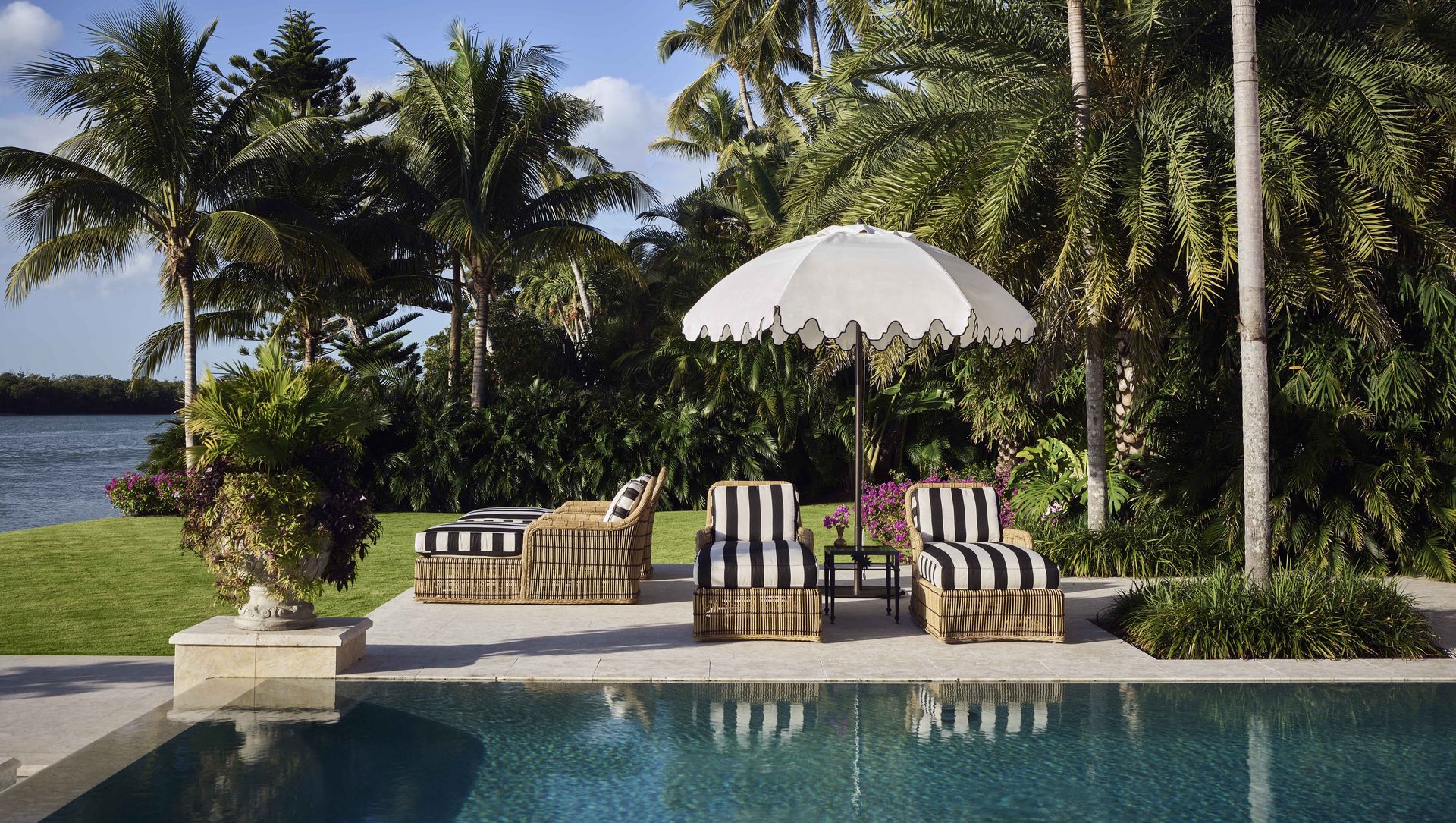 poolside view with black and white striped loungers and a white umbrella