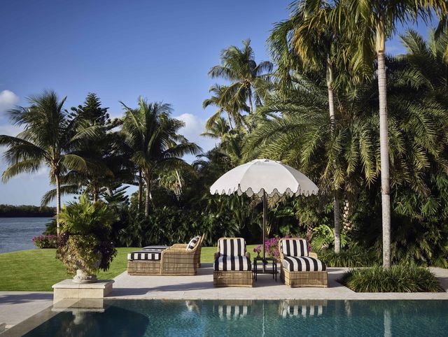 poolside view with black and white striped loungers and a white umbrella