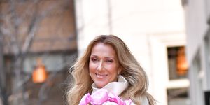celine dion holding a bouquet of flowers and smiling while walking through new york city