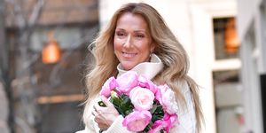 celine dion holding a bouquet of flowers and smiling while walking through new york city