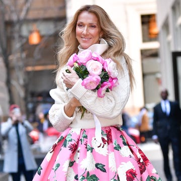 Celine Dion walks around New York City celine dion holding a bouquet of flowers and smiling while walking through new york city