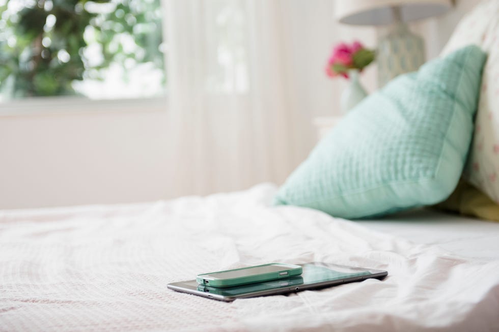 Cell phone and digital tablet on bed