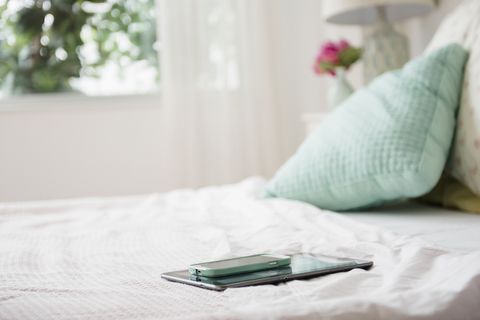 Cell phone and digital tablet on bed
