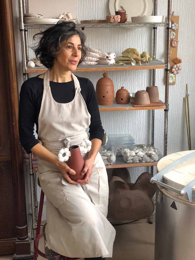 yolanda ruiz ceramista en su taller con estanteria llena de piezas de barro