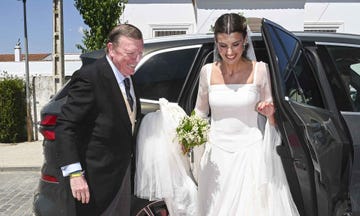 bride stepping out of a car with bouquet in hand