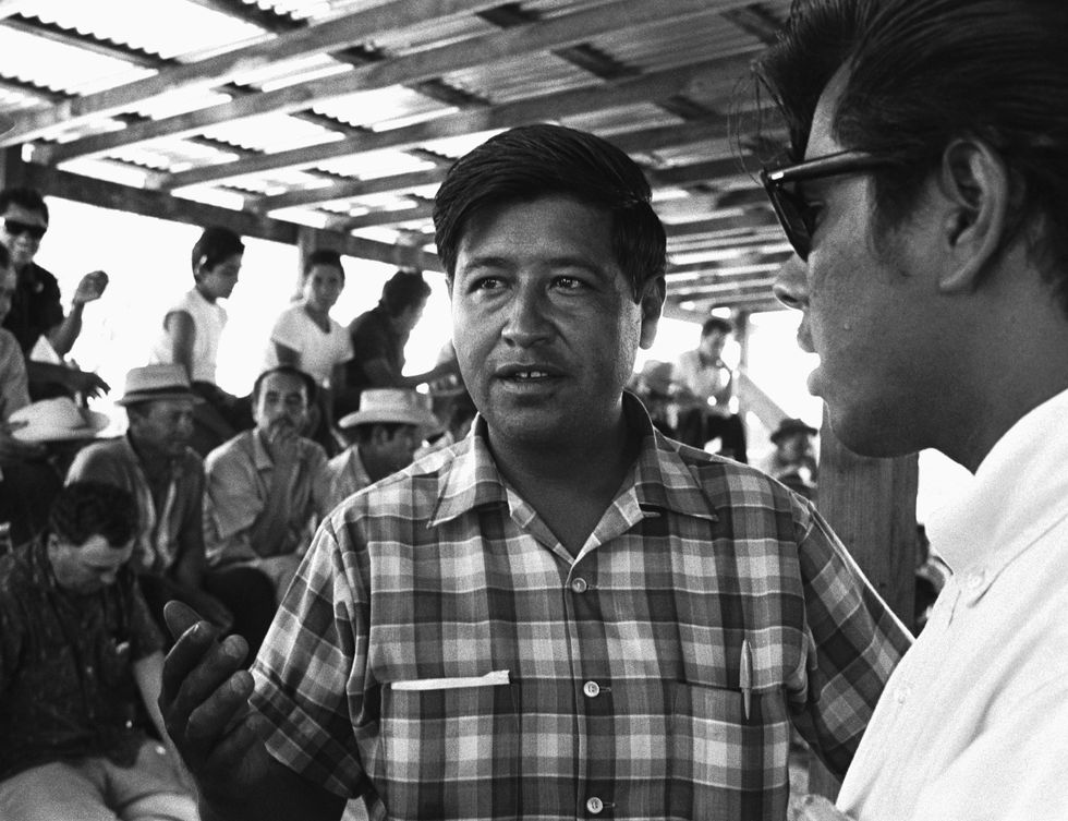 cesar chavez gesturing with his right hand while speaking to another person in the frame