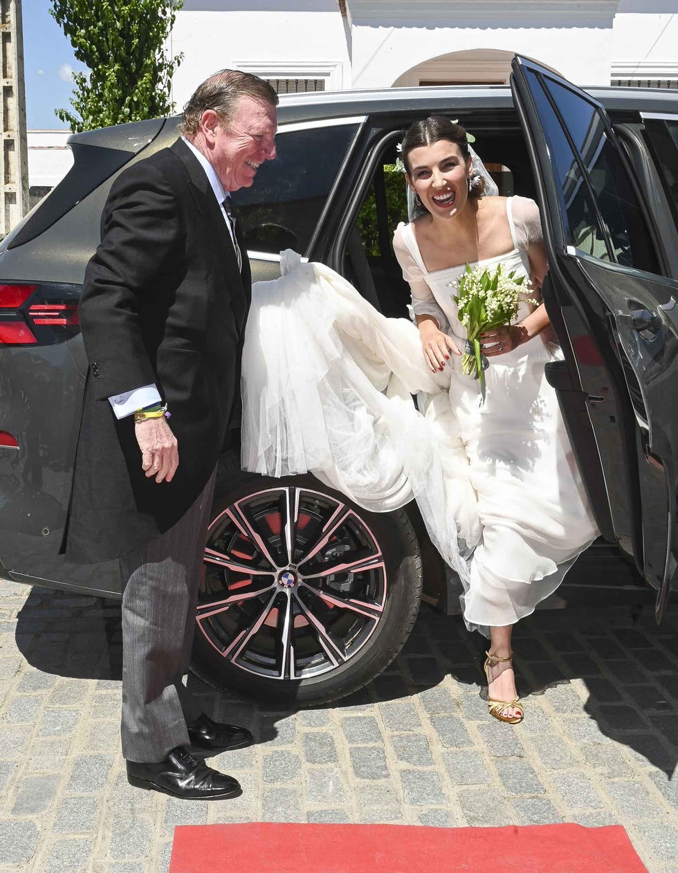 woman in a wedding gown exiting a luxury car