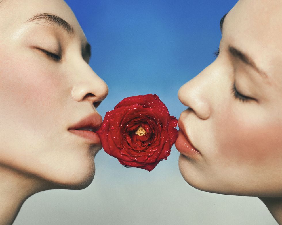 a woman kissing a red flower