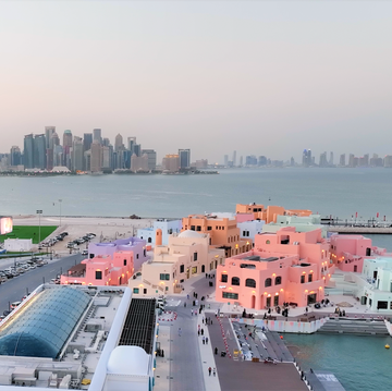 Los mejores restaurantes de Qatar seaside view of a colorful waterfront area with modern buildings and a city skyline in the background