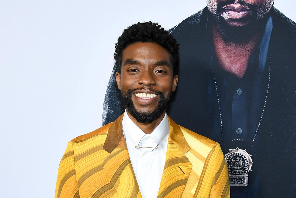 Chadwick Boseman, lächelnd in einer gelben Anzugjacke im November 2019