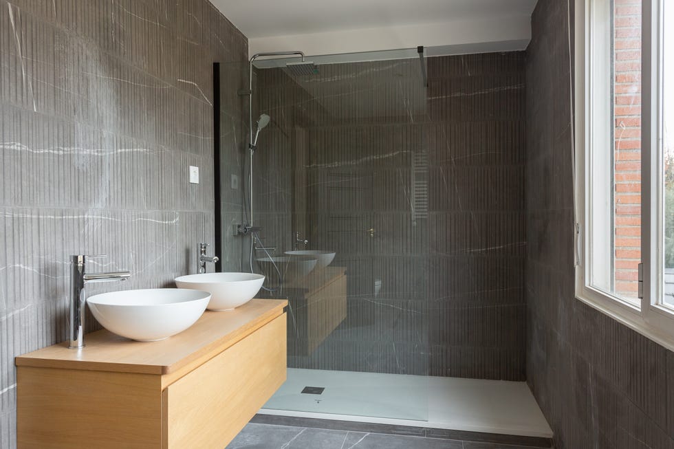 baño moderno con ducha, paredes de hormigón y mueble suspendido de madera