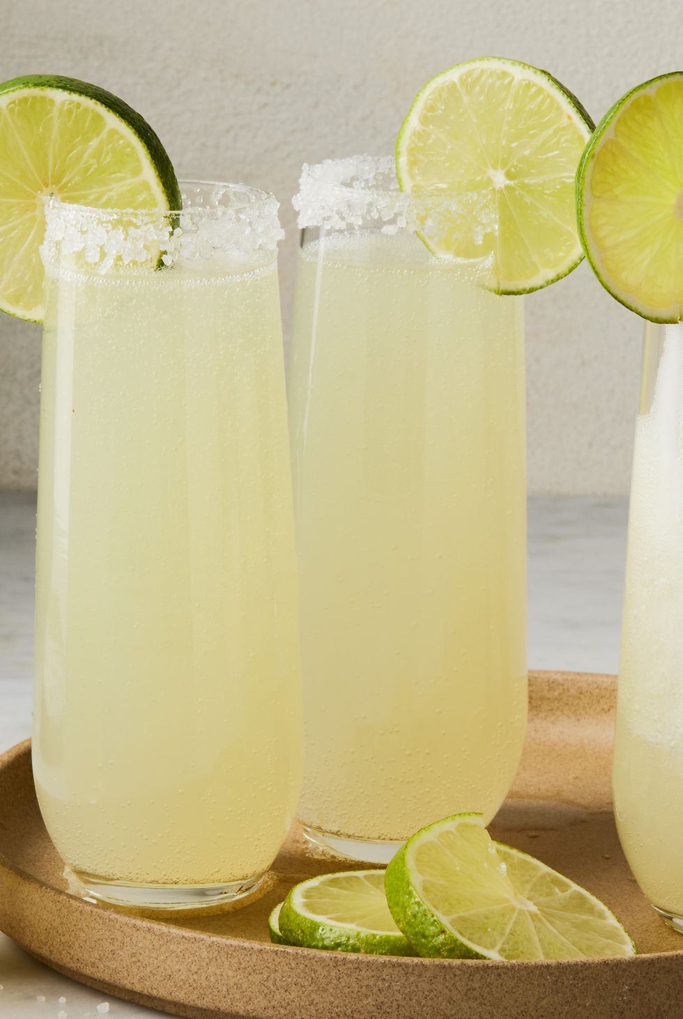 champagne margaritas in flutes rimmed with salt and a lime wheel