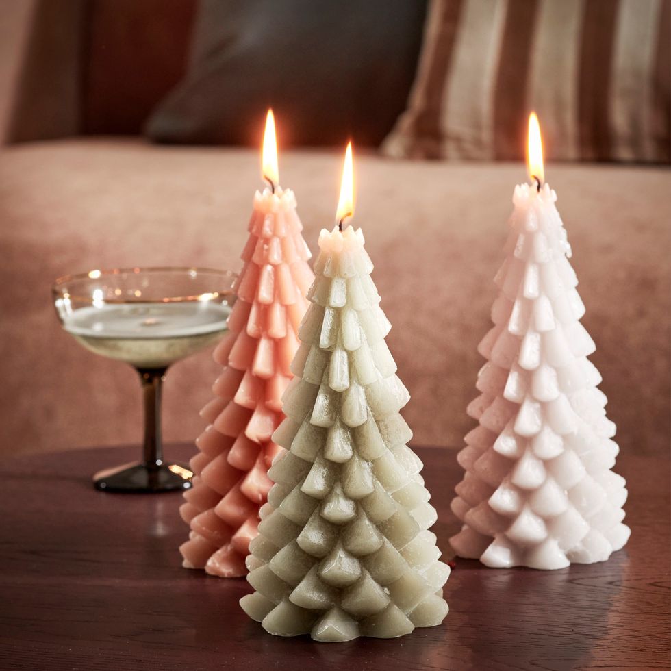 champagneglas naast drie kaarsen in de vorm van kerstbomen