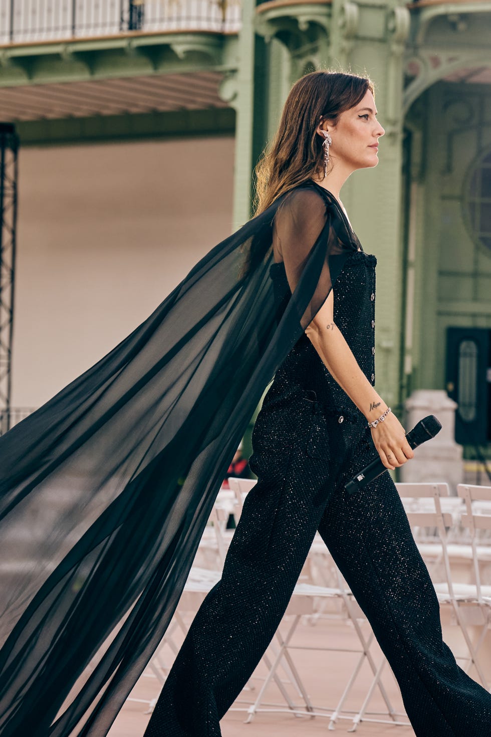 riley keough walking holding a microphone