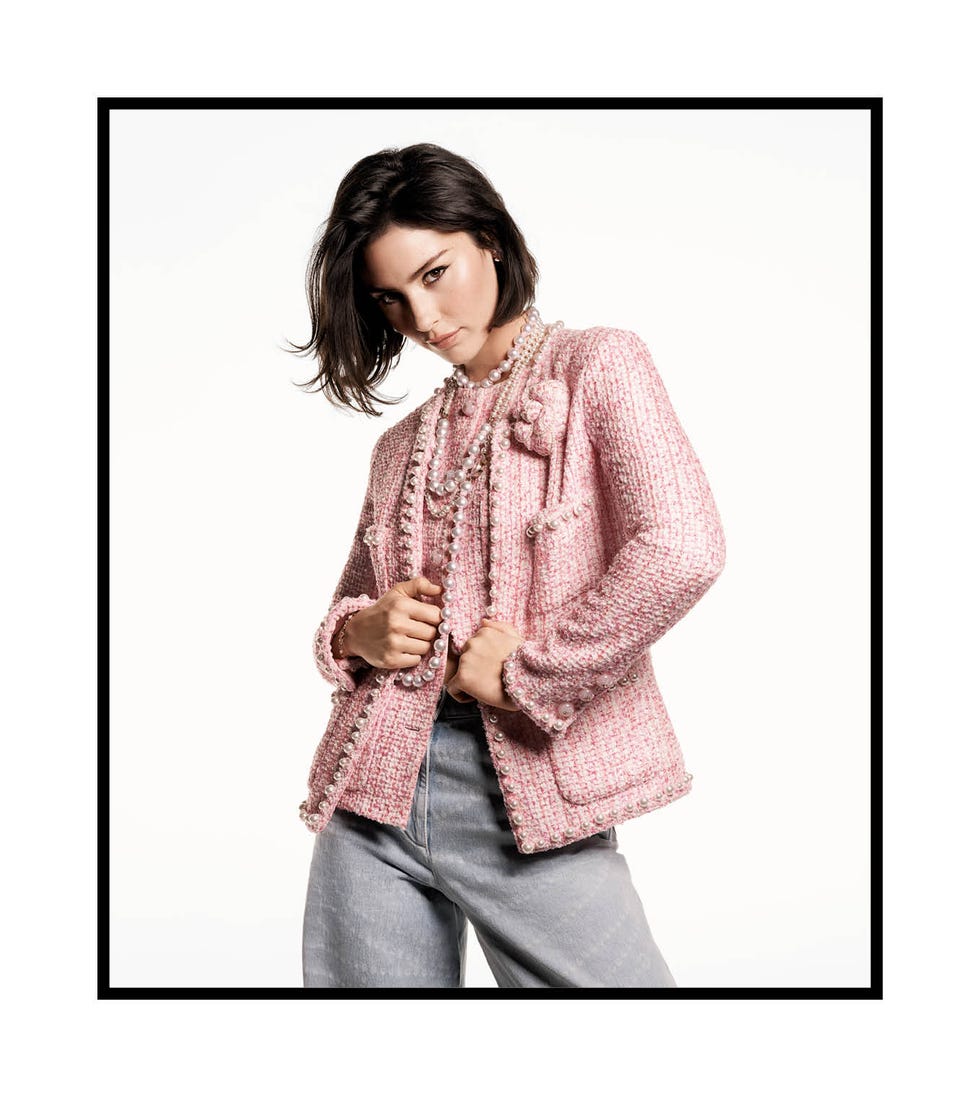 a brunette white woman showcasing a pink tweed jacket with a pearl necklace