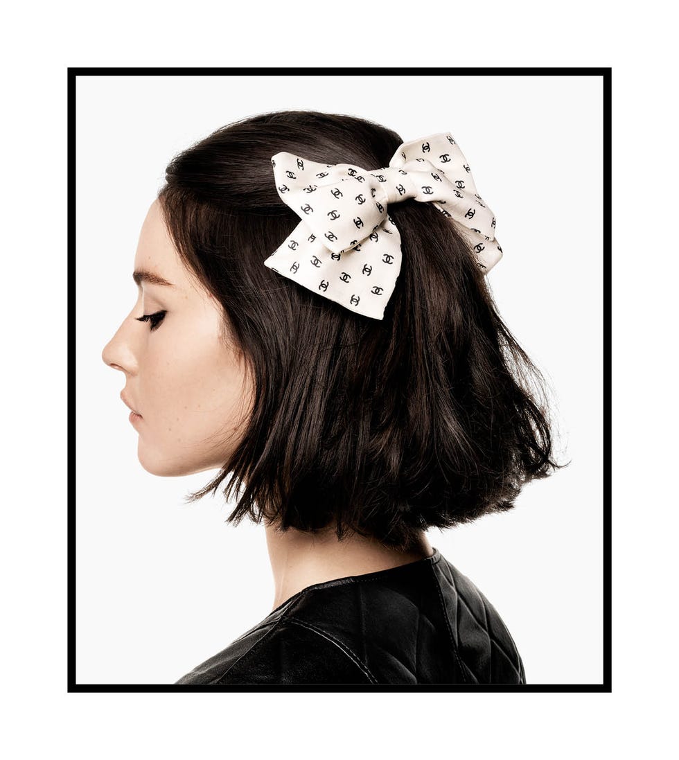 a brunette womans hairstyle featuring a prominent bow accessory